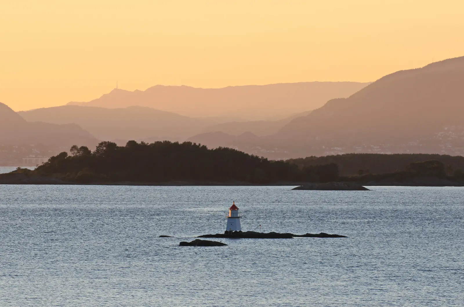 Kveldssol over fjorden ved Tysnes i Sunnhordland, med et lite fyr på et skjær